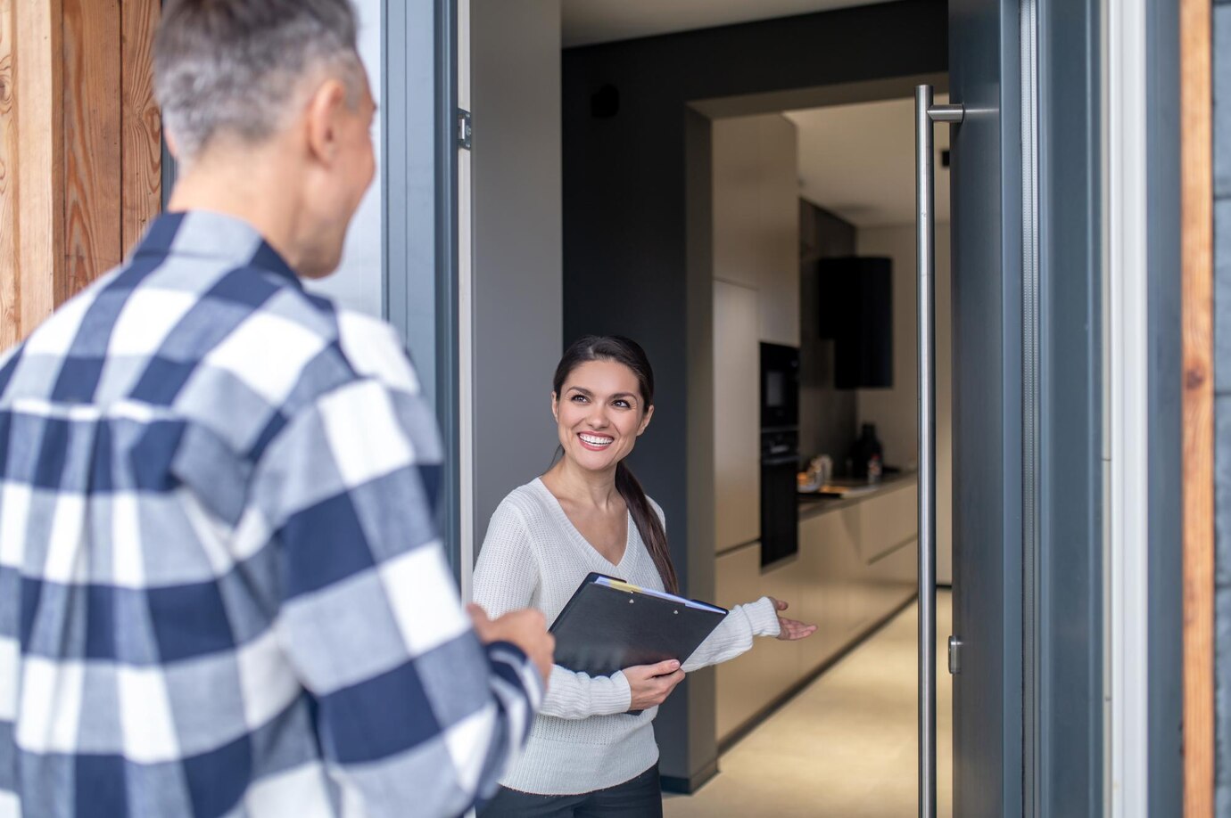 woman-realtor-standing-near-open-door-inviting-man_259150-58376